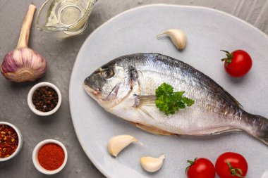 Gri arka planda domates ve baharatlı çiğ dorado balığı tabağı.
