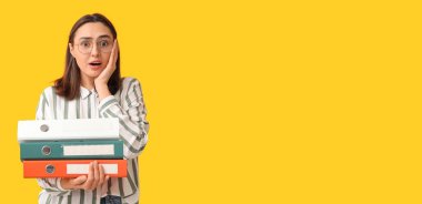 Sarı arkaplan üzerine doküman klasörleri ve metin için yeri olan stresli genç iş kadını