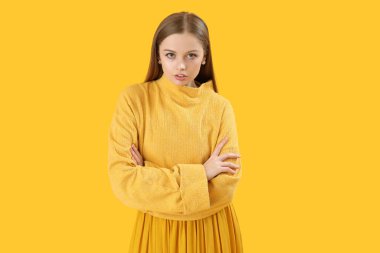 Fashionable young woman in knitted sweater on yellow background
