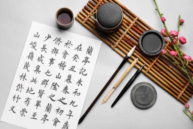 Üzerinde Asya hiyeroglifleri, el yazısı malzemeleri ve arka planda bir fincan çay olan kağıt çarşaf. Uluslararası Haiku Şiir Günü