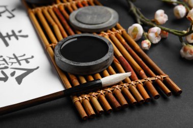 Siyah arka planda mürekkep ve fırçalı bambu hasırı, yakın plan. Uluslararası Haiku Şiir Günü