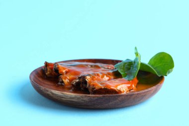 Domates soslu konserve balık tabağı ve mavi arka planda ıspanak yaprakları.