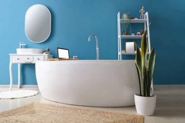 Küvetli banyo, modern dizüstü bilgisayar ve ayna.