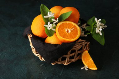 Siyah arkaplanda açan dalları olan bir sepet portakal.