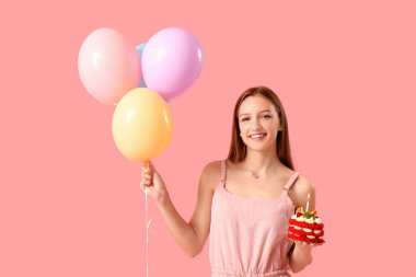 Lezzetli doğum günü pastası ve pembe arka planda balonları olan güzel genç bir kadın.