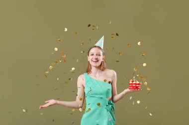 Tatlı doğum günü pastası ve renkli arka planda düşen konfetileri olan güzel genç bir kadın.
