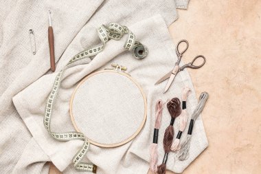 Tuvalli nakış halkası, küflü iplikler ve grunge bej arka planda mezura.