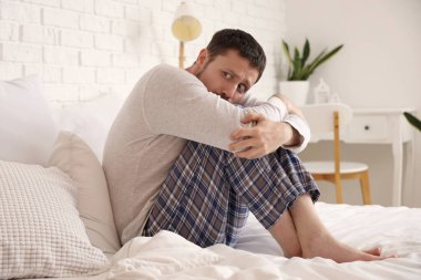 Genç adam yatak odasında panik atak geçiriyor.