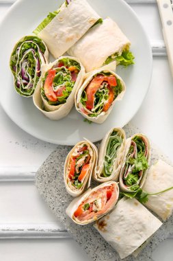 Lezzetli lavaş ruloları ve beyaz ahşap arka planda sebzeler