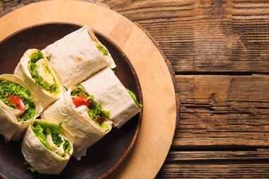 Ahşap arka planda sebzeli ve yumurtalı lezzetli lavaş ruloları.