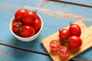 Mavi ahşap arka planda taze kiraz domatesli yemek ve kase.