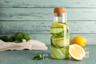 Mavi masada bir şişe salatalık ve naneli limonata.