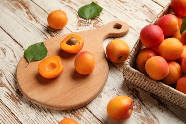 Tahta ve hasır kutu beyaz ahşap arka planda taze kayısılar