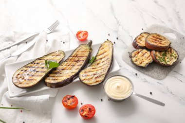 Hafif arka planda ızgara patlıcan, sos ve domates tabağı.