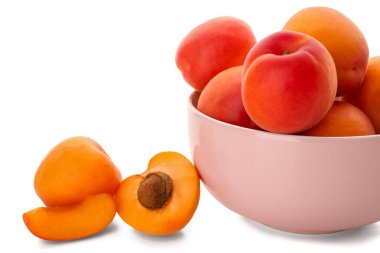 Beyaz arka planda izole edilmiş olgun kayısılarla dolu bir kase.