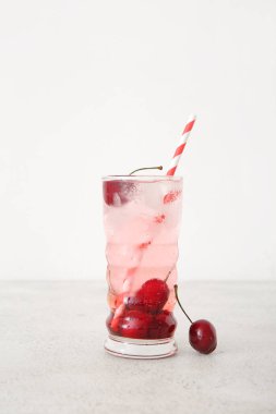 Beyaz arka planda bir bardak kirazlı limonata.