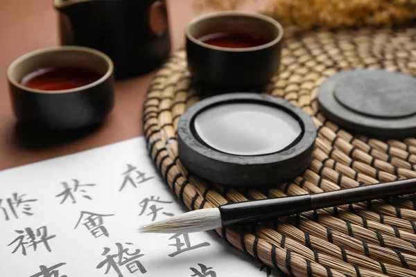 Бумажный Лист Азиатскими Иероглифами Кистью Чернилами Чашками Чая Цветном Фоне — стоковое фото