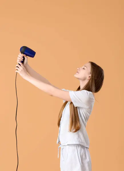 Beautiful young woman with hair dryer on beige background