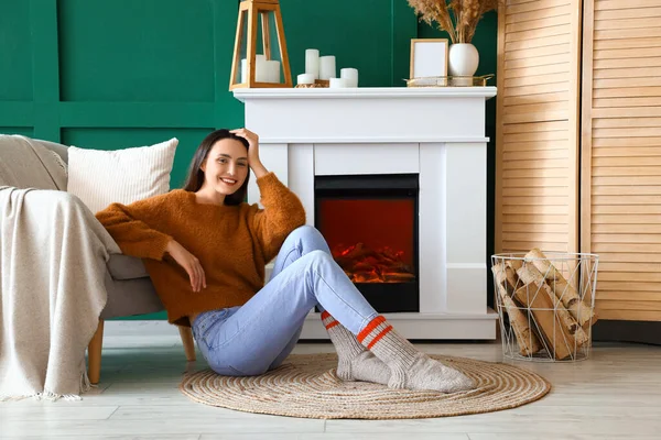 Young woman sitting near fireplace at home