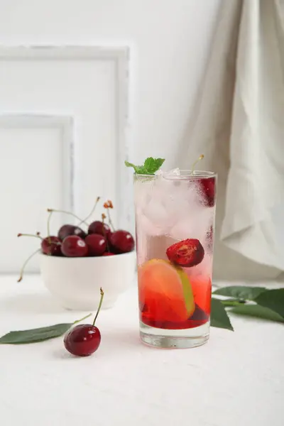 stock image Glass of tasty cherry lemonade and bowl with berries on white background