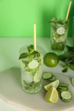 Yeşil arka planda malzemeli bir bardak salatalık mojito.