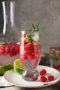 Bardaklar ve bir şişe taze ahududu limonatası ve gri fayanslı biberiye.