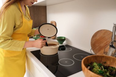 Genç kadın mutfakta çorba yapıyor.