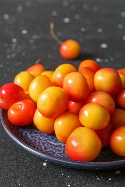 Siyah arka planda sarı kirazlı tatlı bir tabak