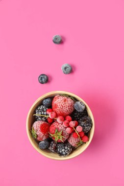 Pembe arka planda bir kase donmuş dut.