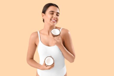 Bej arka planda hindistan cevizi olan güzel genç bir kadın.