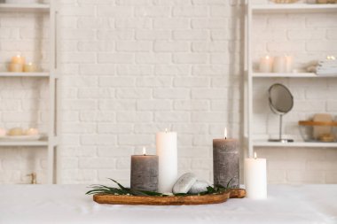 Spa composition with burning candles on couch in salon, closeup