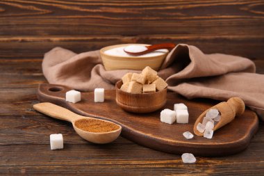 Kase, kaşık ve kepçeyle ahşap arka planda farklı şeker çeşitleri