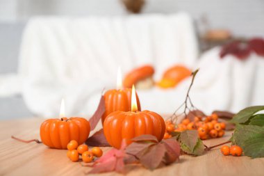 Balkabağı şeklinde yanan mumlar ve odadaki sonbahar yapraklarıyla güzel bir kompozisyon.