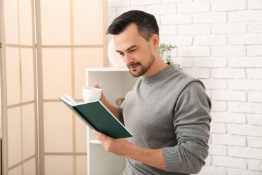 Oturma odasında kahve fincanı okuyan yakışıklı bir adam.