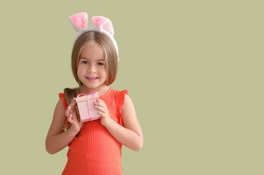 Yeşil arka planda hediye kutusu olan tavşan kulaklı mutlu küçük kız.