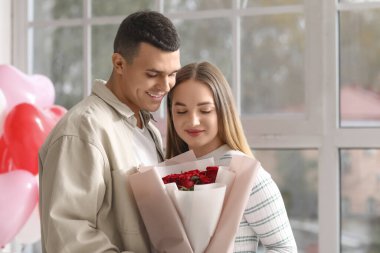 Sevgililer Günü 'nü evde, mutfakta gül buketiyle kutlayan güzel genç bir çift.