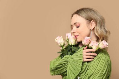 Kahverengi arka planda gül buketi olan güzel genç bir kadın.