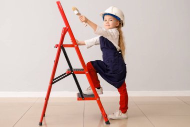 Işık duvarının yanında fırçası ve merdiveni olan şirin bir dekoratör. Karşıt Gün kutlamaları