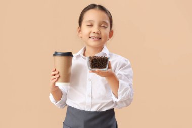 Kahve çekirdekleri ve bej arka planda fincanı olan sevimli bir barista. Karşıt Gün kutlamaları