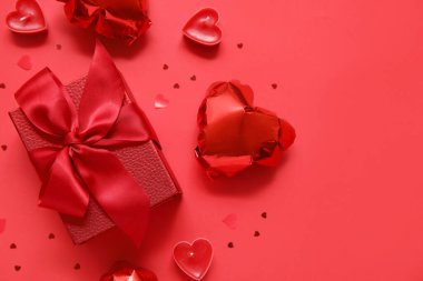 Kalp şeklinde balonları ve kırmızı arka planda mumları olan bir hediye kutusu. Sevgililer Günü kutlaması