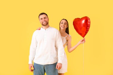 Sarı arka planda kalp şeklinde balonları olan sevimli bir çift. Sevgililer Günü kutlaması