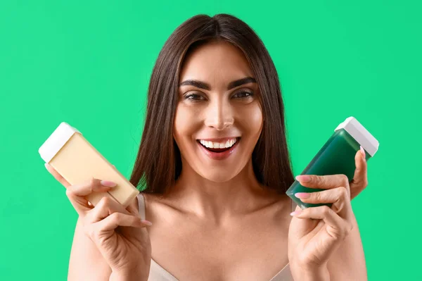 Pretty young woman with wax cartridges on green background. Epilation concept