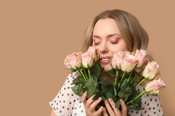 Счастливая молодая женщина с букет красивых роз на коричневом фоне