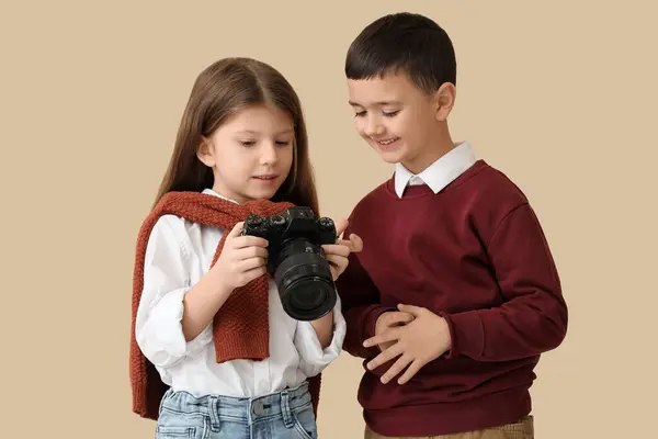 Cute little photographers with camera on beige background. Opposite Day celebration