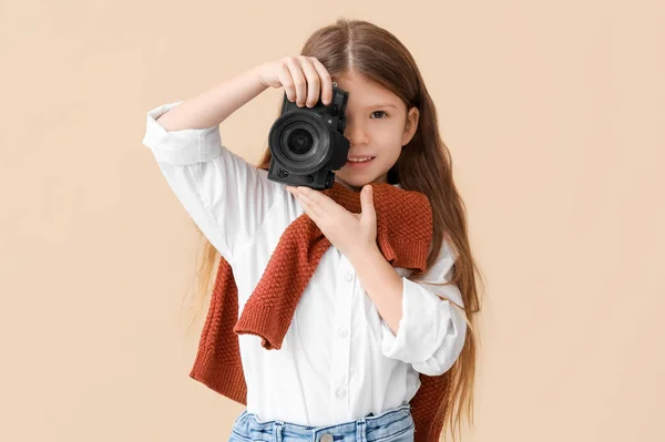 Cute little photographer with camera on beige background. Opposite Day celebration