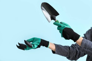 Mavi arka planda küreği olan kadın bahçıvan.