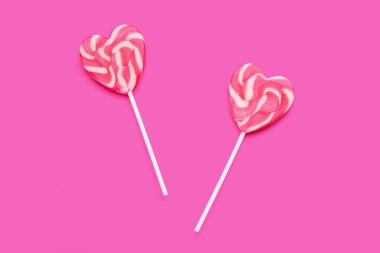 Pembe arka planda kalp şeklinde lolipoplar