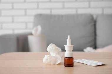 Oturma odasındaki masaya haplar ve mendille burun damlası, yakın plan. Alerji konsepti