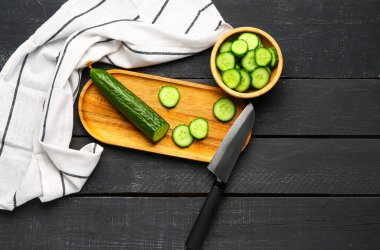 Koyu ahşap arka planda taze kesilmiş salatalık kasesi.