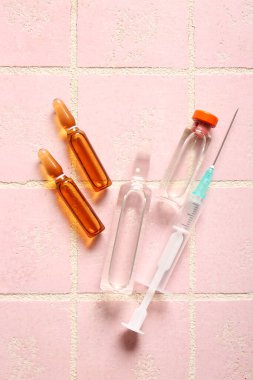Ampule, ilaç şişesi ve pembe fayanslı şırınga.